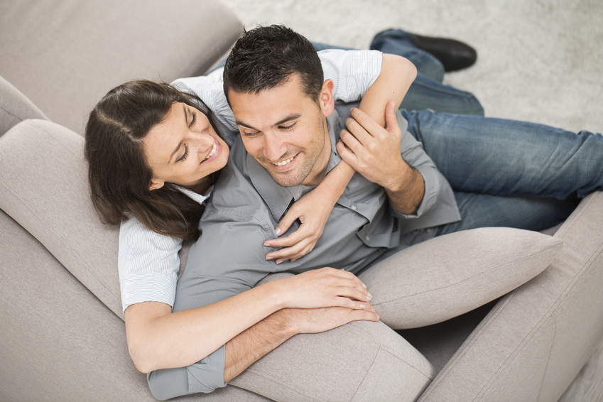 A happy young couple embrace on the sofa