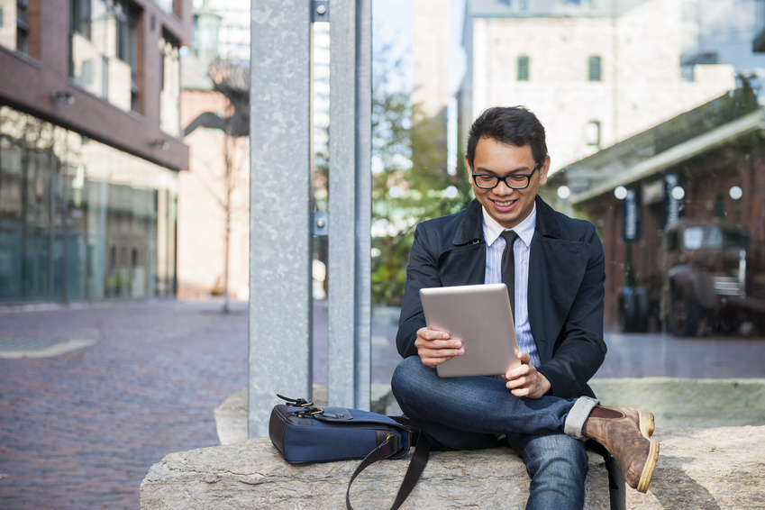 Smiling man sits outside to play PowerBall on his tablet